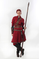 full length portrait of beautiful woman wearing a red medieval fantasy warrior costume with leather armour, holding weapons.  Standing pose isolated on white studio background.