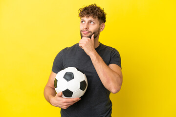 Handsome young football player man isolated on yellow background and looking up