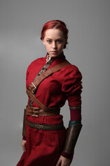  portrait of beautiful woman wearing a red medieval fantasy warrior costume with leather armour.  Standing pose isolated on studio background.