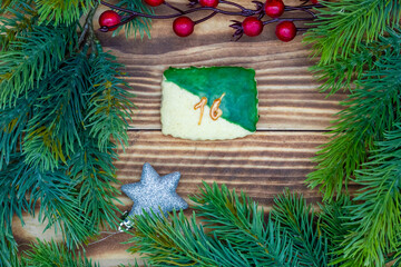leckeres Plätzchen mit einer Zahl (16) auf weihnachtlichen Hintergrund aus Holz