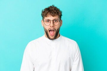 Young handsome caucasian man isolated on blue background With glasses and surprised expression