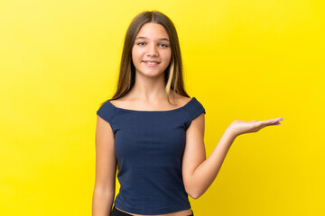 Little caucasian girl isolated on yellow background holding copyspace imaginary on the palm to insert an ad