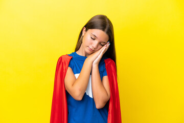 Little caucasian superhero girl isolated on yellow background making sleep gesture in dorable expression © luismolinero