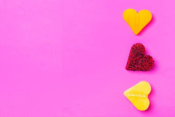 Three pieces of tropical fruits such as pitahaya,mango and a heart-shaped persimmon,on a pink background,copy space.