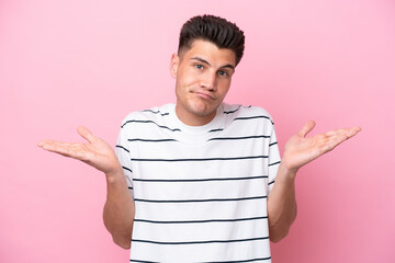 Young caucasian man isolated on pink background having doubts while raising hands