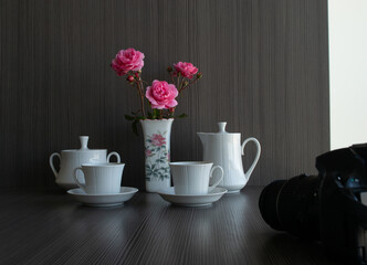 Roses in a vase, coffee set and camera