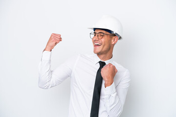 Young architect caucasian man with helmet and holding blueprints isolated on white background celebrating a victory