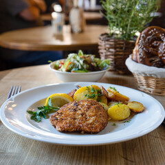 Wiener Schnitzel Essen mit Bratkartoffeln auf einem weißen Teller mit einer Zitronenscheibe