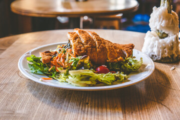 Gemischter grüner Salat Teller mit Wiener Schnitzel Auf einem weißen Teller auf einem Holztisch