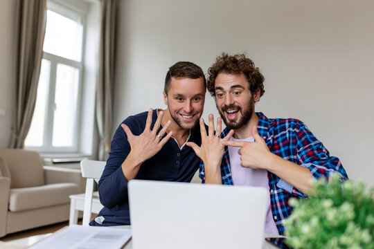 Gay lovers video calling their friends announcing engagement . Two young gay lovers smiling cheerfully while taking online after getting engaged. Happy gay man showing off his ring with his partner.