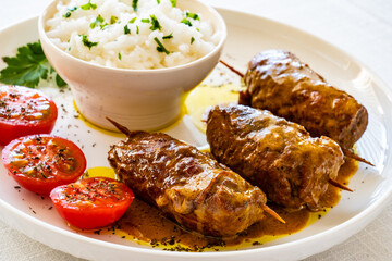 Wrapped pork served with white rice and cherry tomatoes on white table
