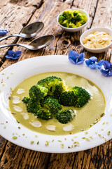 Cream broccoli soup with almonds and oregano on wooden table
