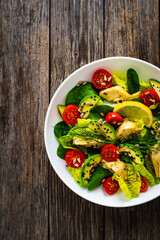 Fresh vegetable salad - avocado, artichoke, lettuce, cherry tomatoes, cucumber, arugula and spinach on wooden table 