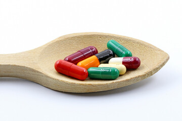 A wooden spoon with medicines or pills