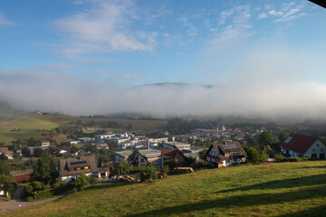 View of the Black Forest town of Baiersbronn with early morning fog in summer