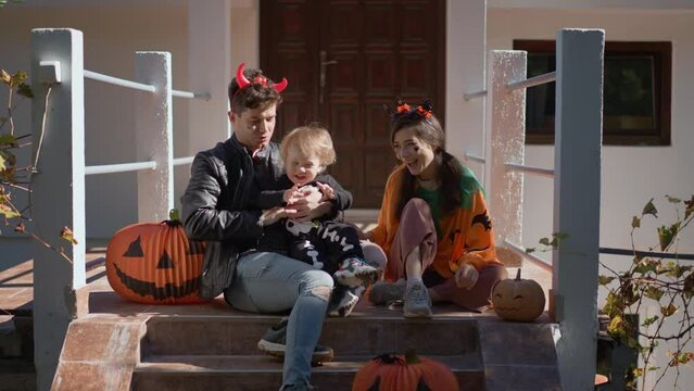 Happy multiethnic family. mother, father and little son celebrate Halloween at sunny day at home on background of pumpkin decorated house. People have fun on traditional fall vibe. Love togetherness
