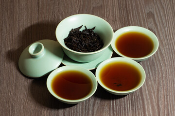 Chinese tea ceremony close-up with selective focus. Brewing Chinese red tea in gaiwan during the tea ceremony. Gaiwan, board and other tea accessories for the ceremony. DaHongPao. Zhu yao.