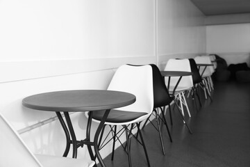 Hostel dining room interior with tables and chairs along white wall