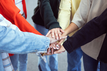 Multiracial young people stacking hands together outdoor - Unity and community concept with diverse...