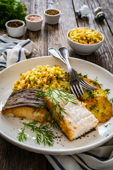 Fish dish - fried halibut with French fries and lemon on wooden table
