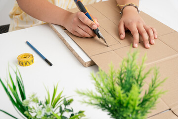 Manos de mujer haciendo manualidades cortando cartón con un cúter