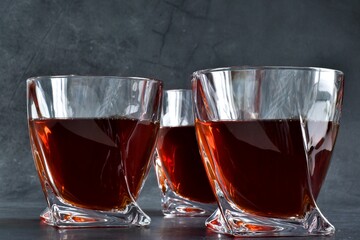 Three glass of cognac on a gray concrete table. Copy space. Selective focus