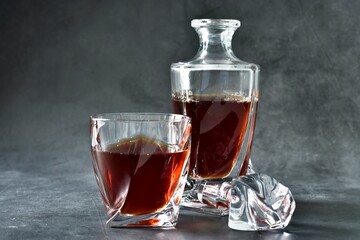 Glass of cognac and decanter on a gray concrete table. Selective focus. Copy space