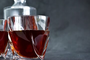 Glasses of cognac and decanter on a gray concrete table. Selective focus. Copy space. Close up