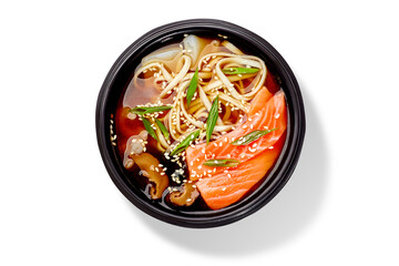 Japanese udon noodle soup with salmon, shrimps and squid served with scallions and sesame