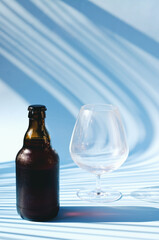 Top view of glass brown beer bottle, glass of beer against blue background close up. Food lifestyle. Alcoholic drink production. Copy space, mockup.
