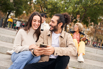 Young woman and man watching something funny at mobile cell. Happy people using phone and having fun. High quality photo
