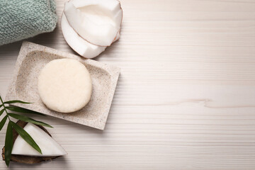 Fototapeta na wymiar Solid shampoo bar, leaf and coconut on white wooden table, flat lay. Space for text