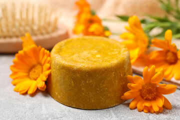 Yellow solid shampoo bar and flowers on light table, closeup. Hair care