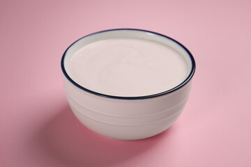Bowl of tasty yogurt on pink background