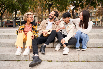 Fototapeta premium Happy friends singing and playing the ukulele outdoors at the city. High quality photo