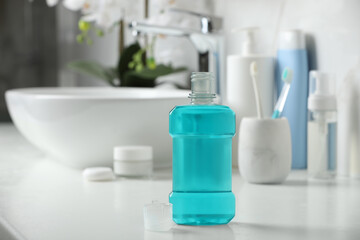 Fototapeta na wymiar Bottle of mouthwash on white countertop in bathroom