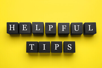 Phrase Helpful Tips made of black cubes with letters on yellow background, top view