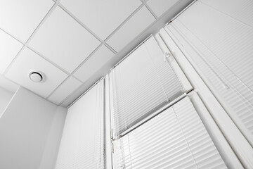 Fototapeta premium Window with closed white horizontal blinds indoors, low angle view