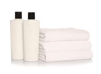 Obraz na płótnie Canvas Folded soft terry towels with cosmetic products on white background