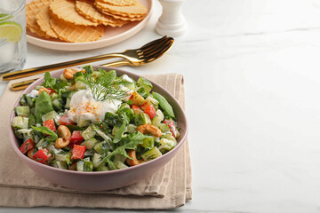 Bowl of delicious cucumber salad served on white marble table. Space for text