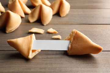 Tasty fortune cookies with predictions on wooden table, closeup. Space for text