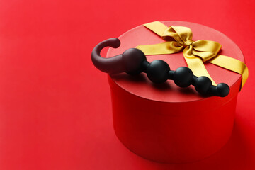Gift box with sex toy on red background. Space for text