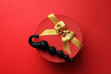 Gift box with sex toy on red background, top view