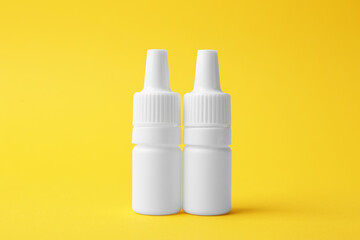 Bottles of medical drops on yellow background