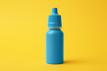 Bottle of medical drops on yellow background