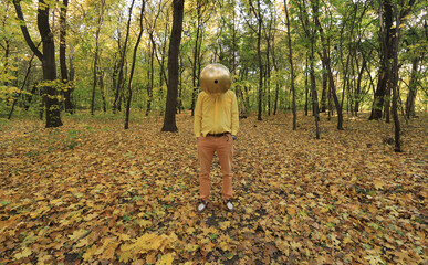 man with a strange golden ball head in the forest