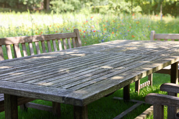 Empty wooden table with bench on sunny day in garden