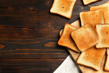 Slices of tasty toasted bread on wooden table, flat lay. Space for text