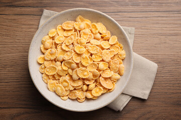 Bowl of tasty corn flakes on wooden table, top view