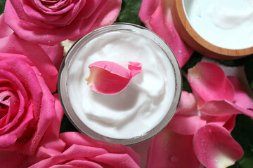 Jar of face cream among beautiful roses, top view